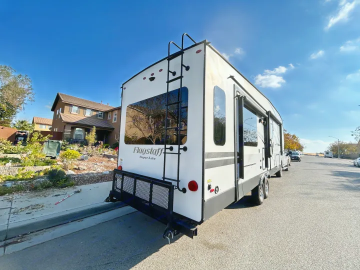 Rear view of a white Flagstaff Super Lite travel trailer, parked on a residential street for RV rental.. Forest River Flagstaff Super Lite 2019
