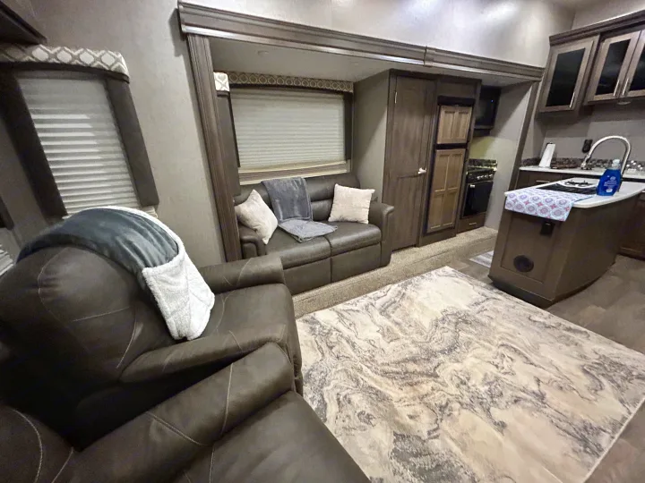 Comfortable RV rental interior. A living space with a recliner and sofa, leading to a compact kitchen area.. Forest River Flagstaff Super Lite 2019