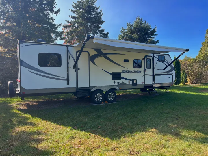 This white Shadow Cruiser travel trailer is set up in a sunny campsite, perfect for an RV rental adventure.. Cruiser RV Shadow Cruiser 2015