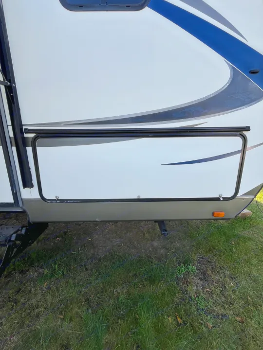 Exterior view of an RV rental, showing a large side storage compartment and access steps, parked on grass.. Cruiser RV Shadow Cruiser 2015