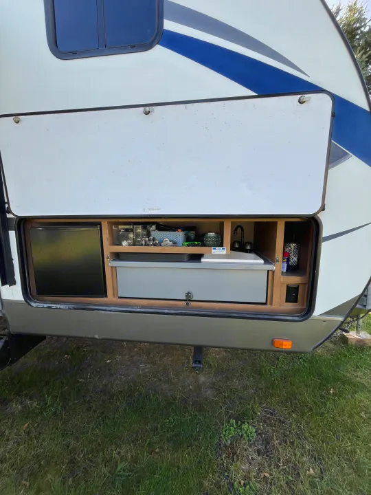 This RV rental's outdoor kitchen bay reveals a mini-fridge, sink, and organized storage shelves, perfect for trips.. Cruiser RV Shadow Cruiser 2015