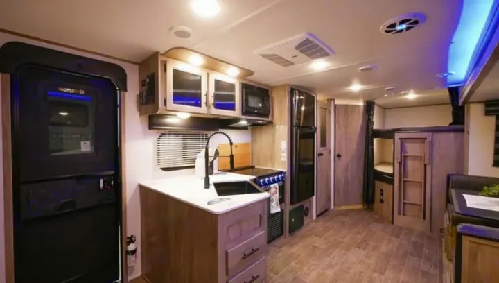 Spacious RV rental interior with a well-equipped kitchen, large refrigerator, and cozy bunk beds for comfortable travel.. Forest River Cherokee Alpha Wolf 2021