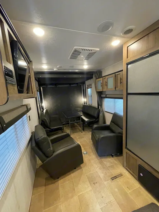Spacious RV rental interior featuring recliners, benches, a dining table, and kitchen amenities. Perfect for comfortable travel.. Palomino Puma 2021