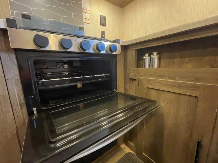 Inside this rv rental, a compact kitchen oven with its door open shows the racks, part of a functional interior.. Palomino Puma 2021