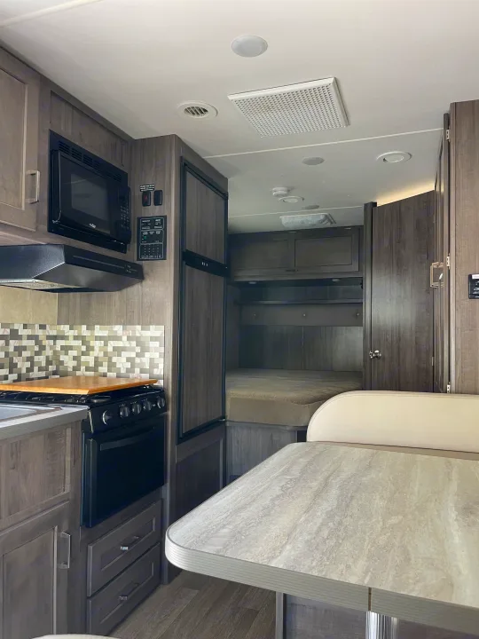 Inside a spacious rv rental, showcasing a fully-equipped kitchen, dining area, and comfortable sleeping bunk in a modern design.. Winnebago Minnie Winnie 2019