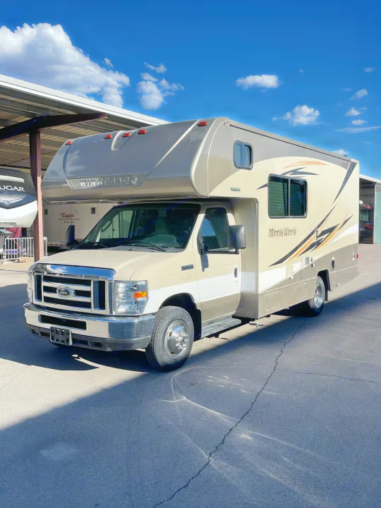 Beige Winnebago Minnie Winnie Class C motorhome RV rental, parked in sunlight under a blue sky with clouds.. Winnebago Minnie Winnie 2019
