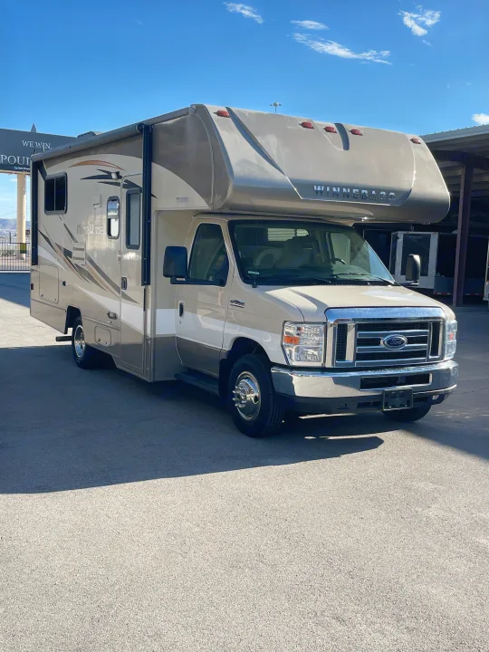 A light-colored Winnebago Minnie Winnie Class C RV, ideal for rv rental and outdoor adventures, parked on asphalt under a blue sky.. Winnebago Minnie Winnie 2019
