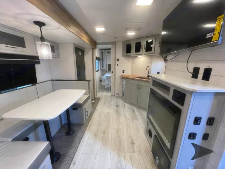 Spacious RV rental interior featuring a modern kitchen, comfortable dining booth, and an entertainment living space.. Heartland RVs North Trail 2024