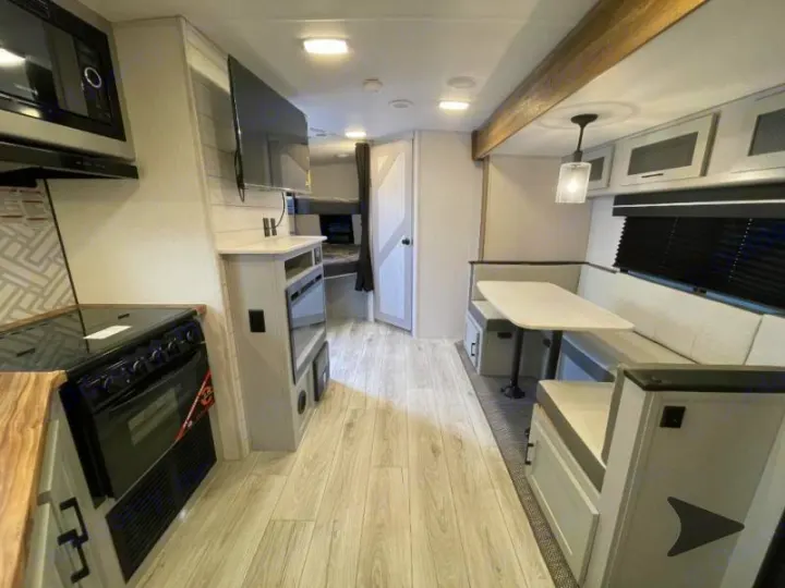 Spacious RV rental interior: modern kitchen, dining, living, and bunk bed areas. Bright, light finishes.. Heartland RVs North Trail 2024
