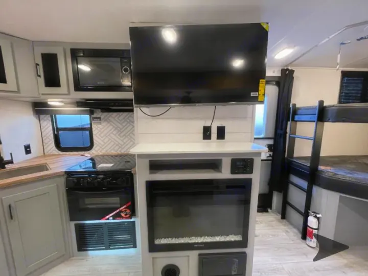 RV rental interior features a kitchen, TV, electric fireplace, and bunk beds.. Heartland RVs North Trail 2024