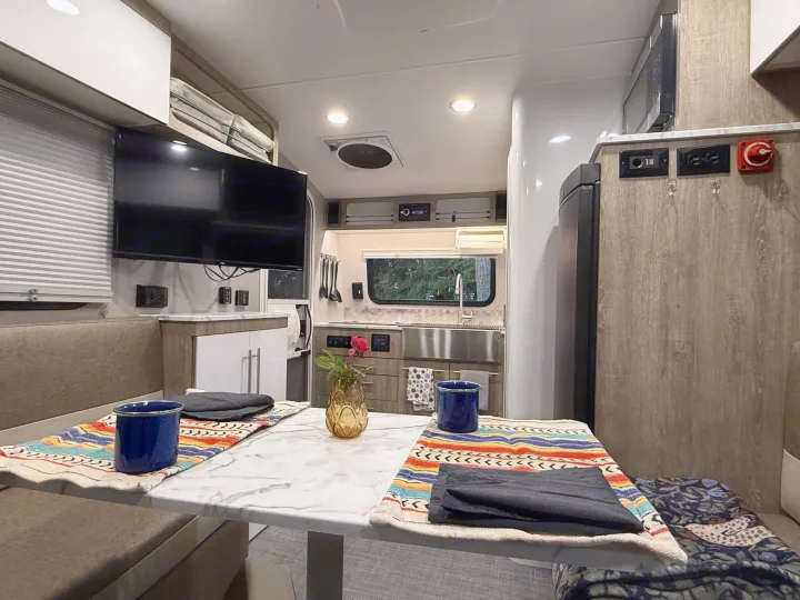 This RV rental's cozy interior features a full kitchen, dining nook, and entertainment center, perfect for road trips.. InTech RV SOL 2021