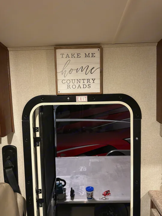 RV rental: Open RV door to a toy hauler garage with items and a red vehicle. 'Home' sign and 'EXIT' above the door.. FR3 FR3 Motorhome 2018