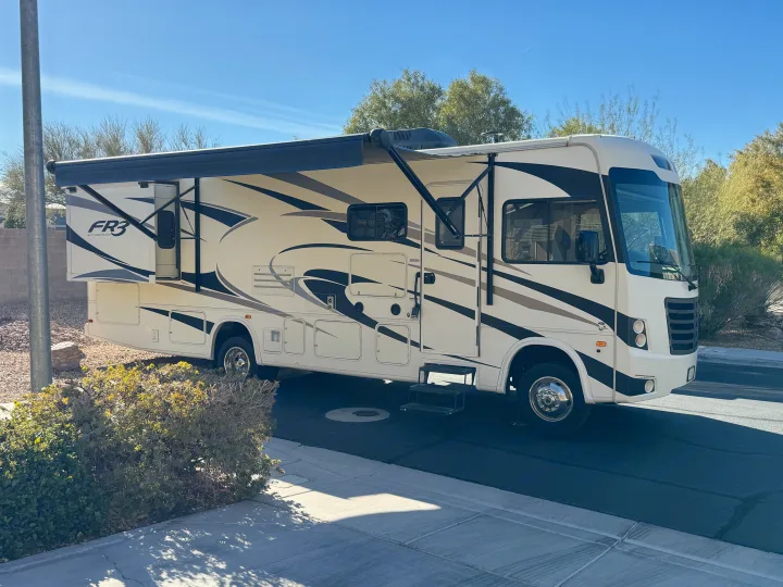 A cream and black Forest River FR3 Class A RV rental with an extended awning & slide-out, parked on a sunny street.. FR3 FR3 Motorhome 2018