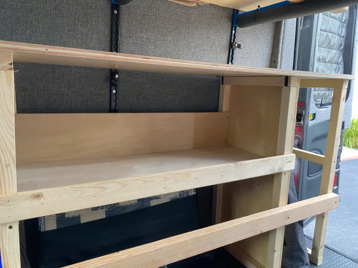 Custom wooden shelving inside an RV rental van, offering practical storage solutions in the built-out interior.. Ford Transit 2016