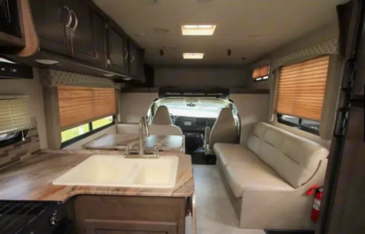 This bright rv rental interior features a functional kitchen, comfortable dinette, and easy access to the driver's cockpit.. Coachmen Freelander 2018