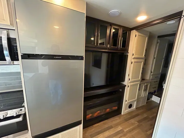 Spacious RV rental interior featuring kitchen, living area with modern appliances, TV, and electric fireplace.. Entegra Odyssey 30Z 2024