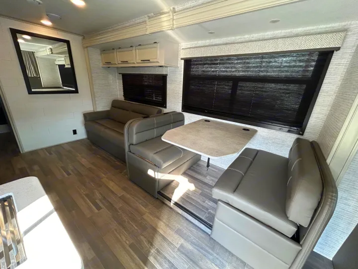 Spacious RV rental interior with modern dinette, sofa, and wood-look flooring. Perfect for your next adventure.. Entegra Odyssey 30Z 2024