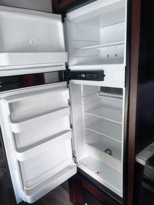 An open, empty Norcold RV refrigerator in an rv rental, showing shelves and controls, ready for your trip.. Jayco Jay Flight SLX 2018