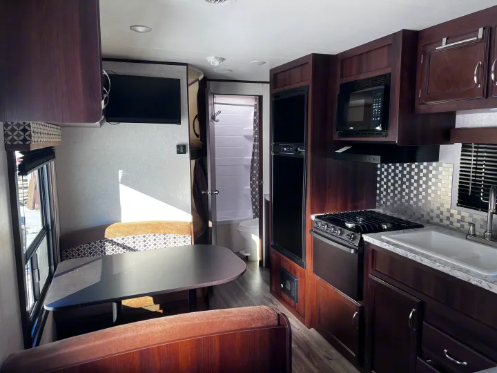 Spacious RV rental interior featuring a full kitchen, dining area, living space with TV, and a compact bathroom. Perfect for travel.. Jayco Jay Flight SLX 2018
