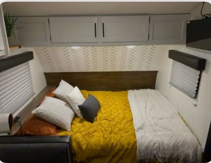 Cozy RV rental bedroom with white cabinets, patterned wall, and a comfortable bed. Perfect for your next adventure.. Forest River Cherokee Wolf Pup 2022