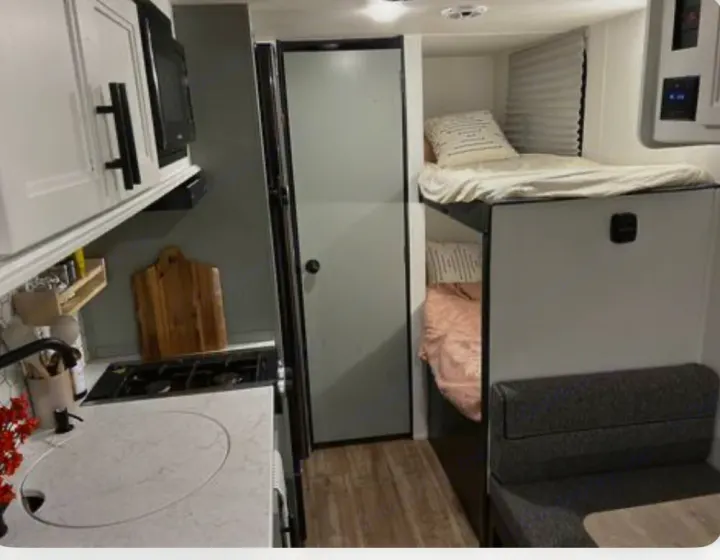 Explore this modern RV rental's cozy interior, featuring a full kitchen, comfortable bunk beds, and a versatile dinette area.. Forest River Cherokee Wolf Pup 2022