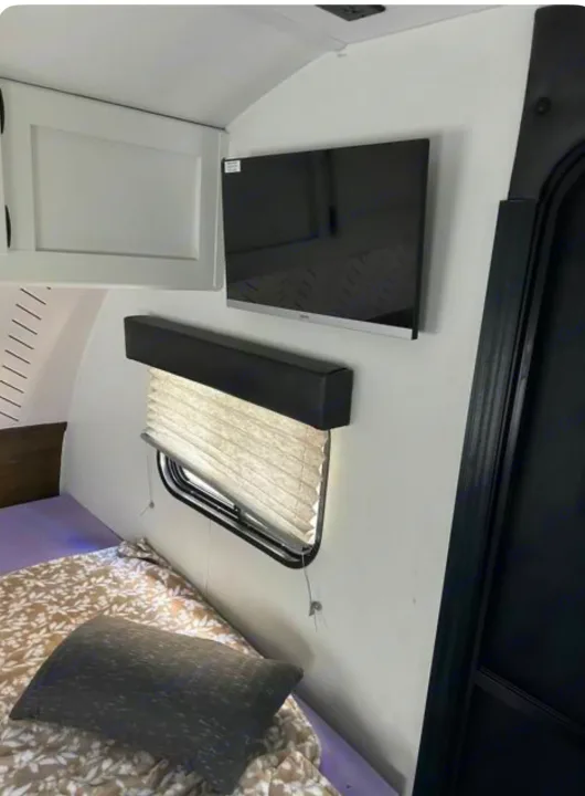 Inside a comfortable rv rental: bed, mounted TV, window, and overhead cabinet for a cozy travel experience.. Forest River Cherokee Wolf Pup 2022