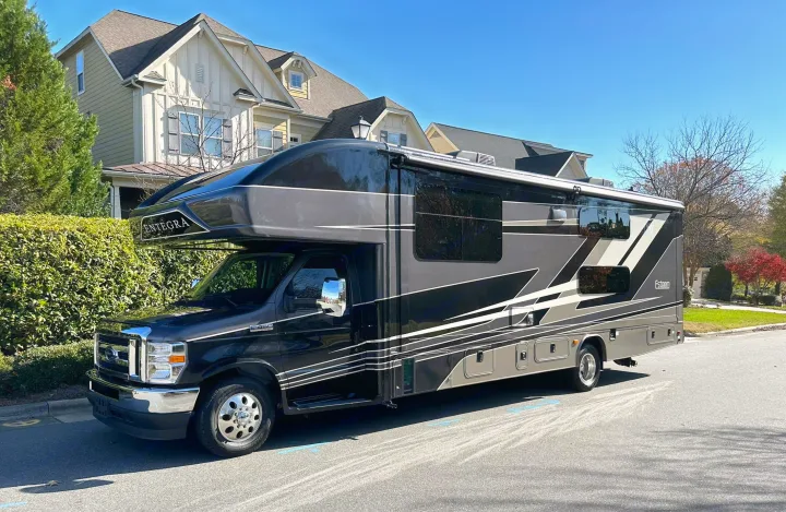 A sleek black and gray Entegra Esteem Class C RV, perfect for your next rv rental adventure, parked on a sunny street.. Entegra Coach Esteem 2023