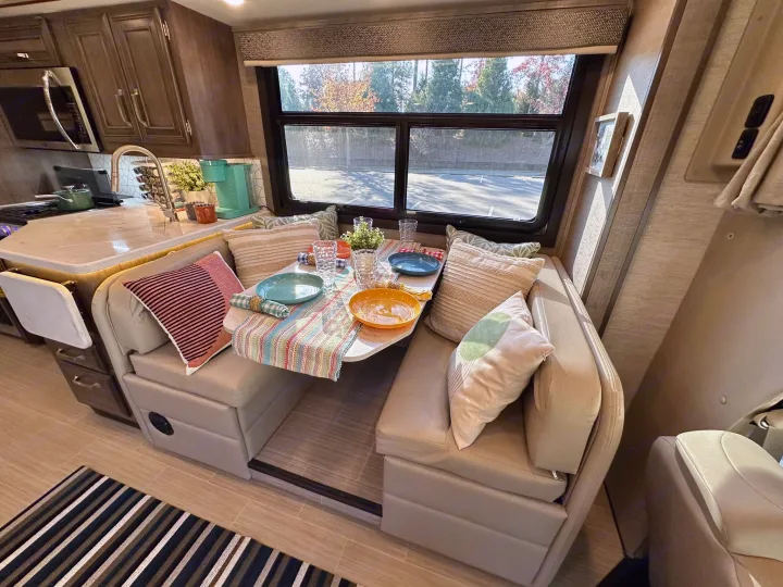 Inside a modern RV rental: a comfortable dinette with kitchen and scenic window views.. Entegra Coach Esteem 2023