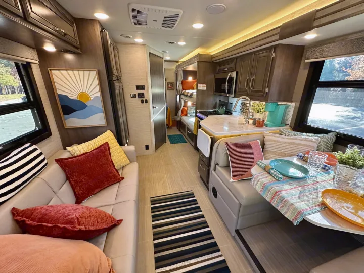 Bright RV rental interior with living area, full kitchen, dining nook, and bunk beds, offering comfort on the road.. Entegra Coach Esteem 2023