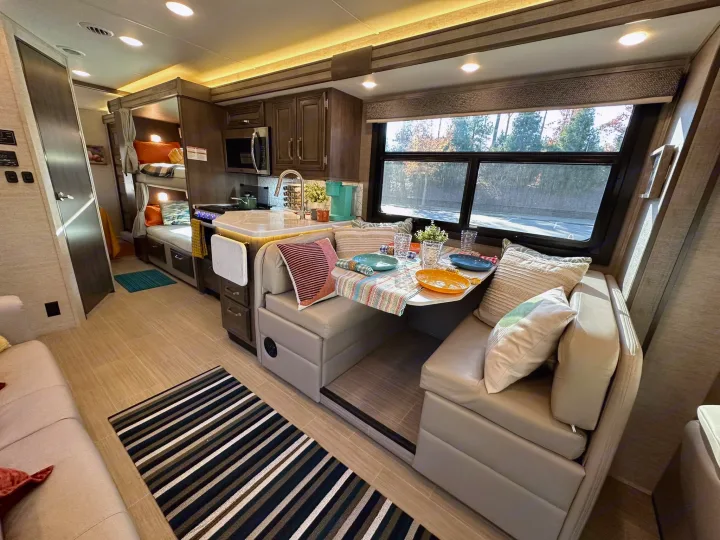 Spacious RV rental interior with a cozy dinette, modern kitchen, comfy sofa, and practical bunk beds for family trips.. Entegra Coach Esteem 2023