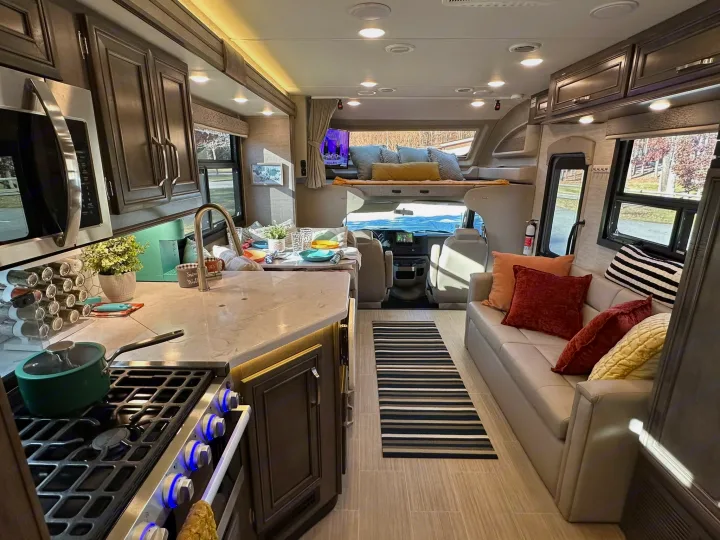 Explore this spacious RV rental, showcasing a modern kitchen area, inviting living space, and comfortable cab-over bunk.. Entegra Coach Esteem 2023
