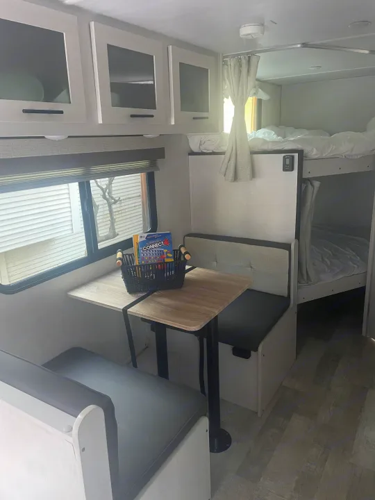 RV rental interior featuring a bright dinette, overhead cabinets, and cozy bunk beds, ideal for travel.. No Boundaries NoBo 19.3 Essentials Only 2024