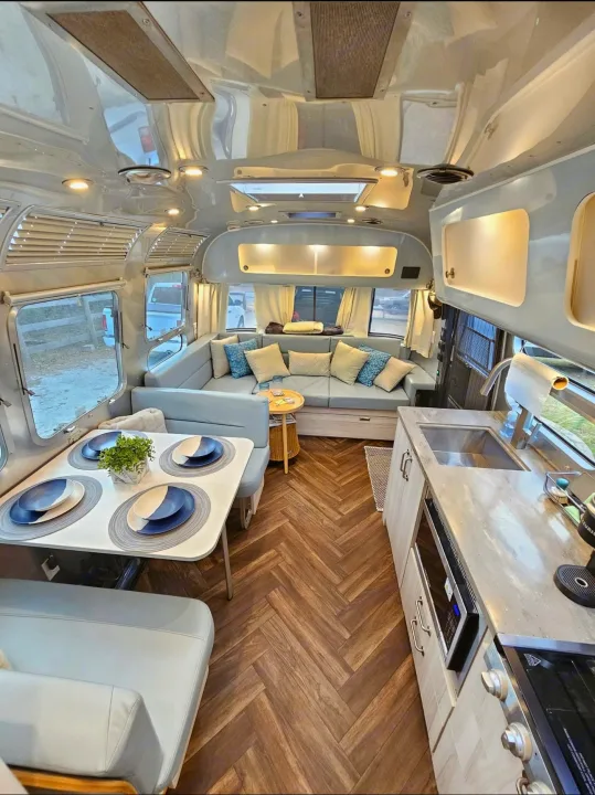 This bright Airstream RV rental showcases a versatile interior with a modern kitchen, dining nook, and inviting lounge.. Airstream International 2022