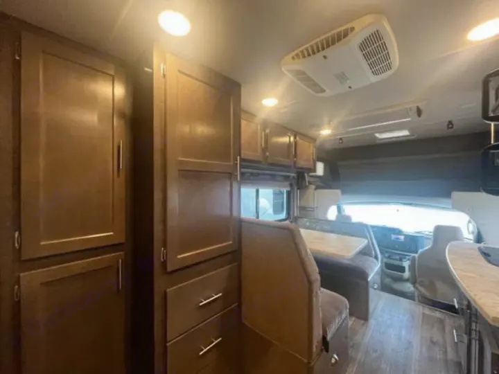 View inside an RV rental showing wood cabinets, a dining area, and the driver's cab. Ideal for road trips.. Adventurer Adventurer Motorhome 2017