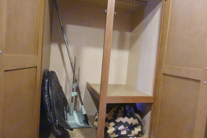 RV rental closet: Organized storage with cleaning supplies (broom/dustpan), a black bag, and a woven bag under a shelf.. KZ Spree 2017
