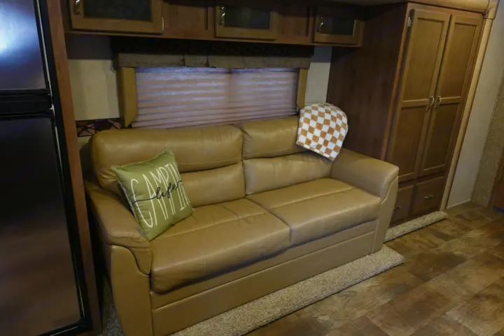 Relaxing RV rental living space: Tan leather sofa, window, cabinets, and fridge visible for comfortable travels.. KZ Spree 2017