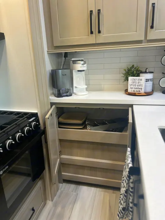 RV rental kitchen counter with coffee station, modern appliances, and storage for plates & cutlery.. Grand Design Momentum 2025