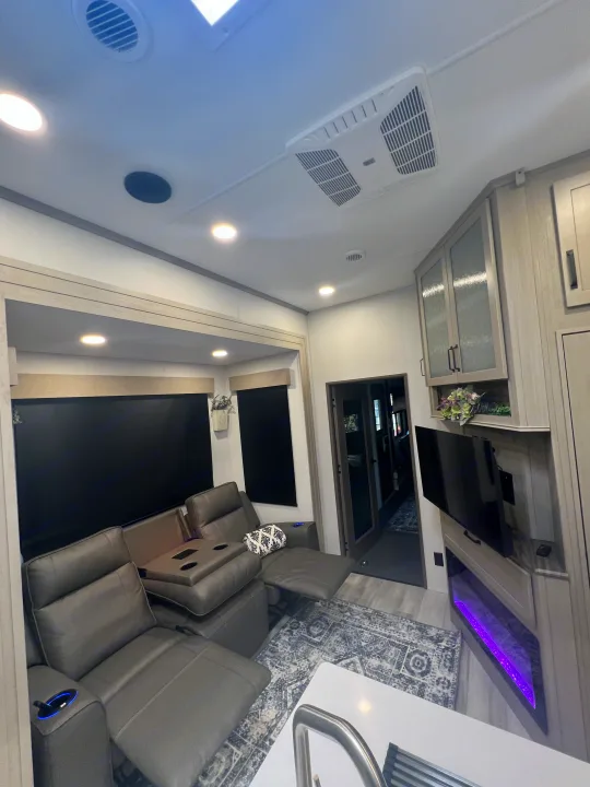 Spacious RV rental living area with reclining seats, modern fireplace, and bright lighting for ultimate comfort.. Grand Design Momentum 2025
