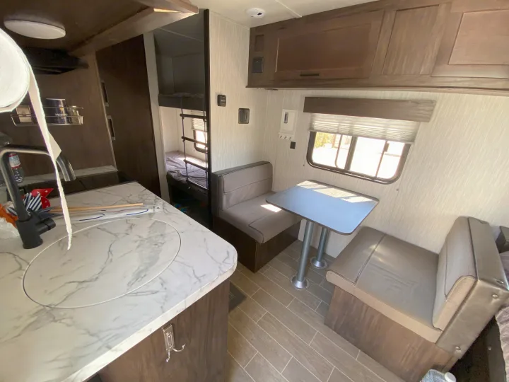 RV rental interior: kitchen counter on left, bunk beds center, dinette and window on right.. Forest River Cherokee Wolf Pup 2020