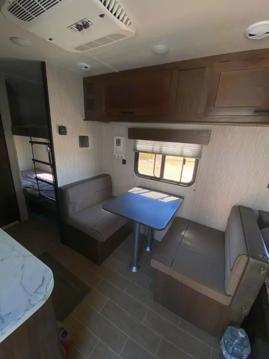 RV rental interior featuring a practical dinette, bunk beds, and overhead cabinets for a comfortable travel experience.. Forest River Cherokee Wolf Pup 2020