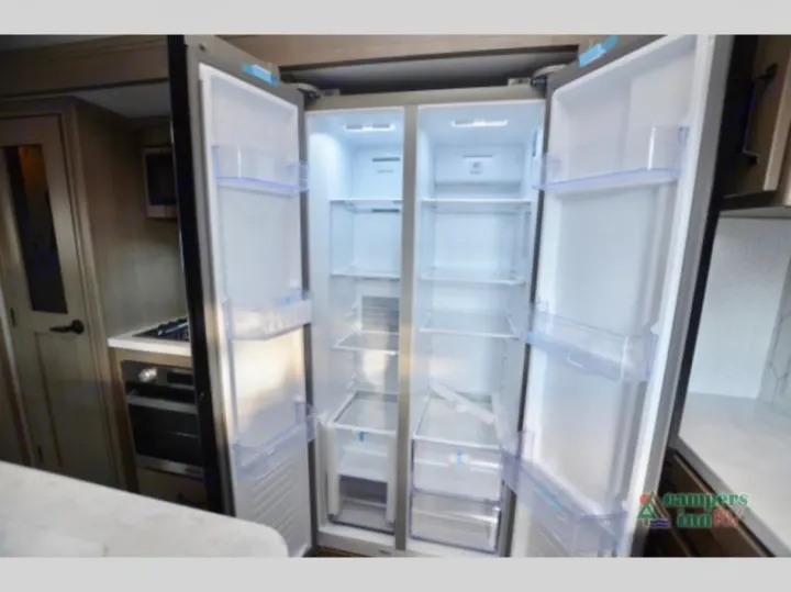 Inside a modern RV kitchen, featuring an open, spacious side-by-side refrigerator. Ideal for your rv rental adventure.. Grand Design Reflection 2023