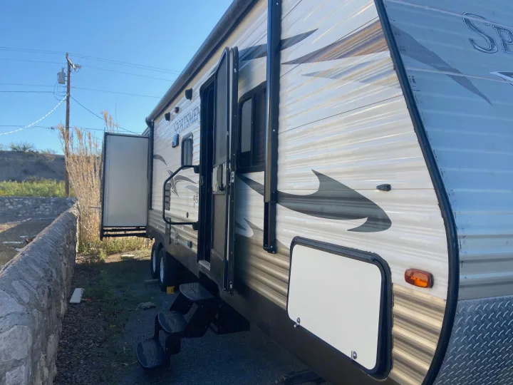 Side view of a spacious RV rental, parked with its door and storage compartment open, ready for outdoor adventures.. KZ Sportsman 2015