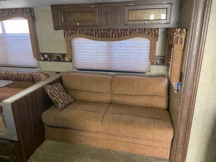 Comfortable RV rental interior featuring a dinette, sofa, and overhead cabinets. Perfect for your next road trip adventure.. KZ Sportsman 2015