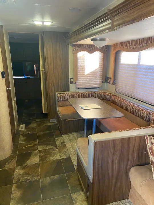 Spacious RV rental interior featuring a comfortable dining booth and a view into the hallway/kitchen area.. KZ Sportsman 2015
