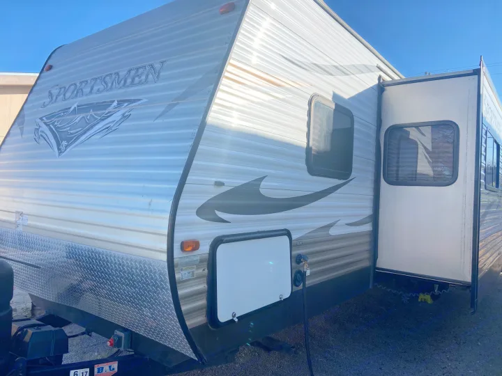 Silver 'Sportsmen' travel trailer RV rental with an opened slide-out, ready for your next adventure.. KZ Sportsman 2015
