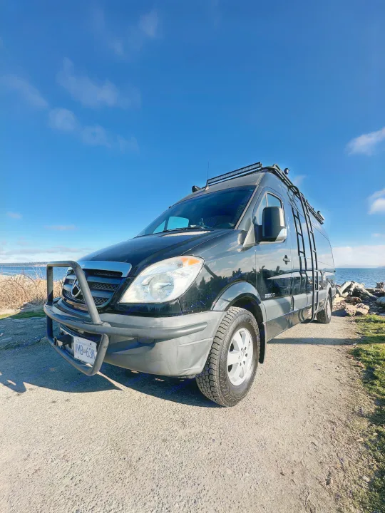 A robust black Mercedes Sprinter camper van, great as an RV rental, parked ocean-side for adventure travel.. Mercedes Sprinter 2007