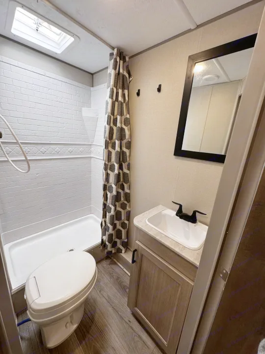 This RV rental bathroom features a clean shower, toilet, and sink vanity, perfect for your next trip.. Coachmen Catalina Summit Series 8 261BHS 2025