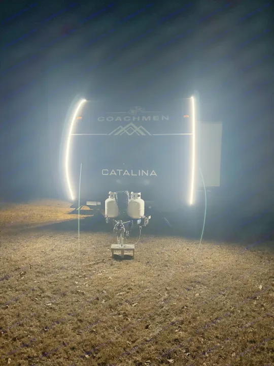 Nighttime view of a lit Coachmen Catalina travel trailer, ideal for your next RV rental trip, parked on a grassy field.. Coachmen Catalina Summit Series 8 261BHS 2025