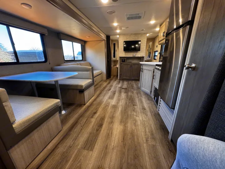 Modern RV rental interior with dinette, living area with TV, kitchen, wood-look floor, and light decor.. Coachmen Catalina Summit Series 8 261BHS 2025