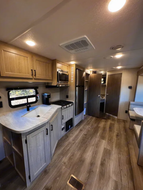 Modern RV rental interior with full kitchen, dining booth, and ample living space for comfortable travels.. Coachmen Catalina Summit Series 8 261BHS 2025